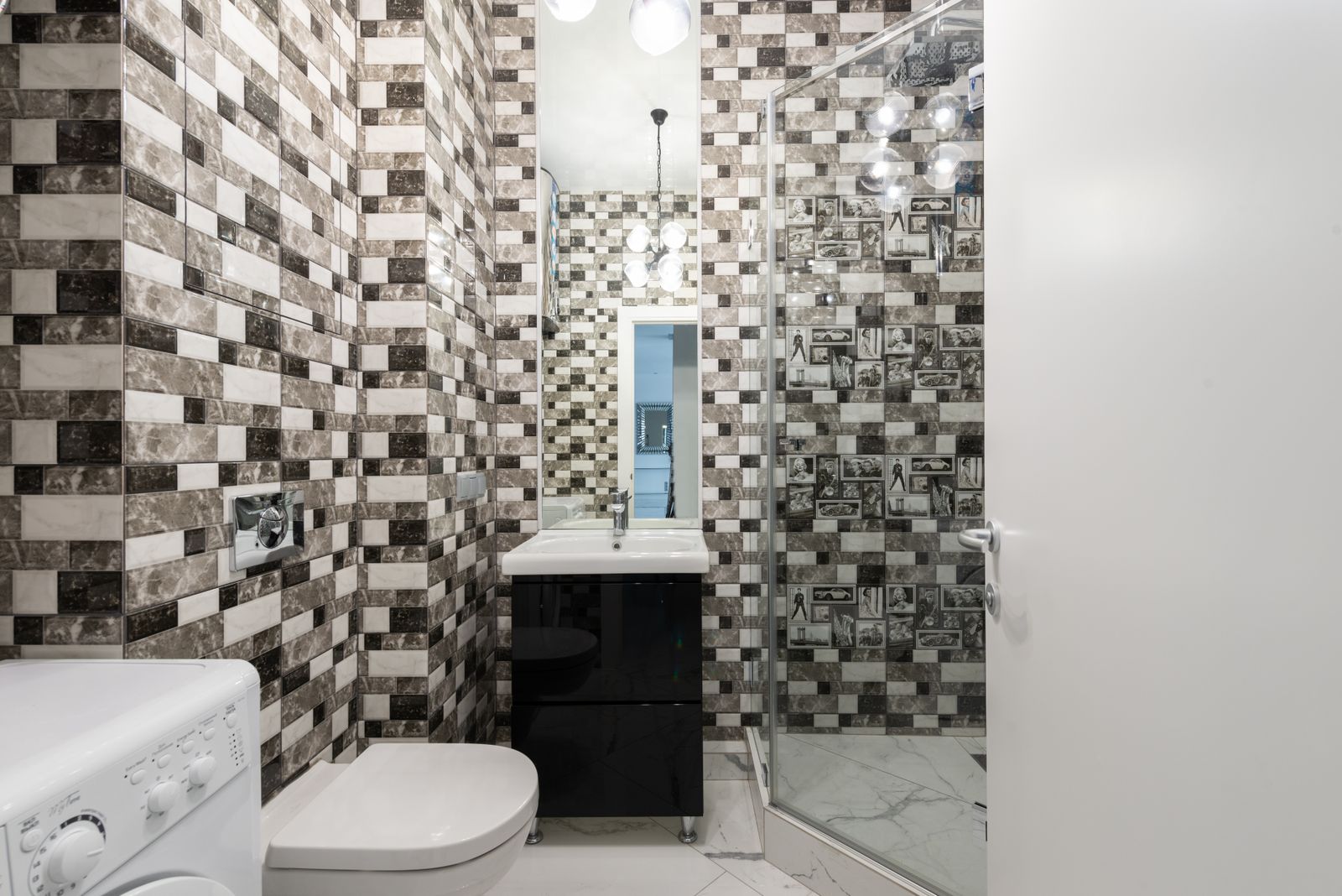 Interior of bright washroom with washing machine near toilet next to shower and sink with tap