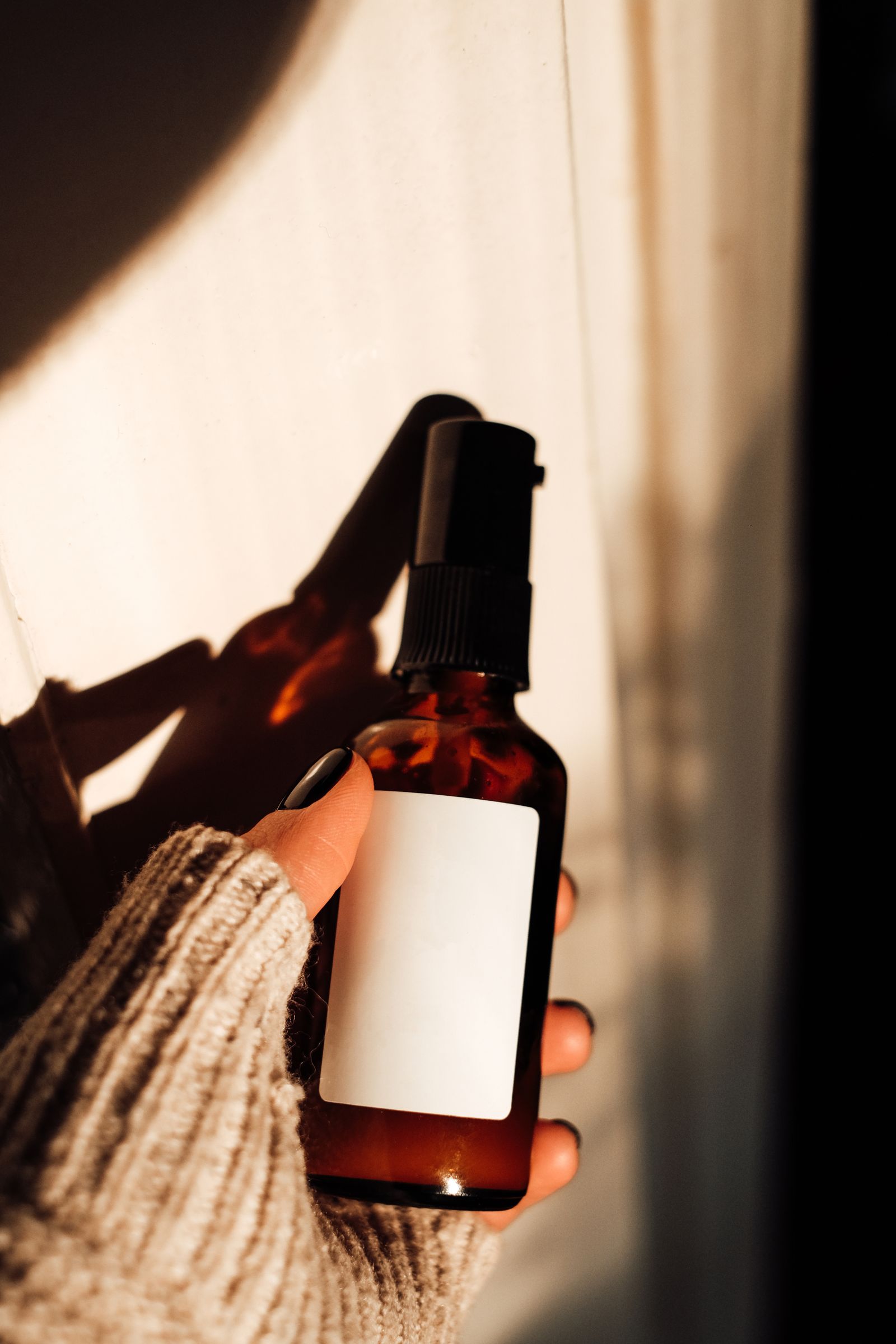 Hand holding an amber glass spray bottle